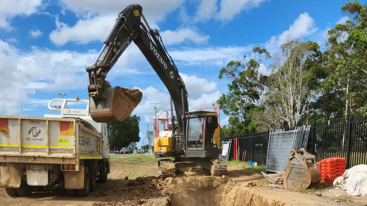 An excavator loads dirt into a dump truck - Wamuran Irrigation Scheme